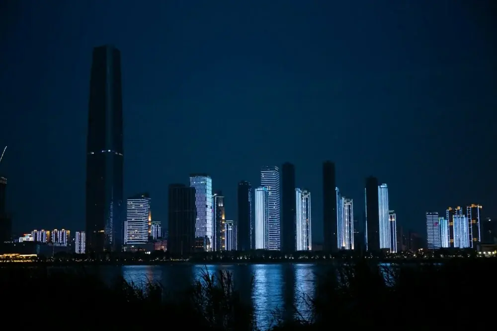 a city at night with a body of water in front of it