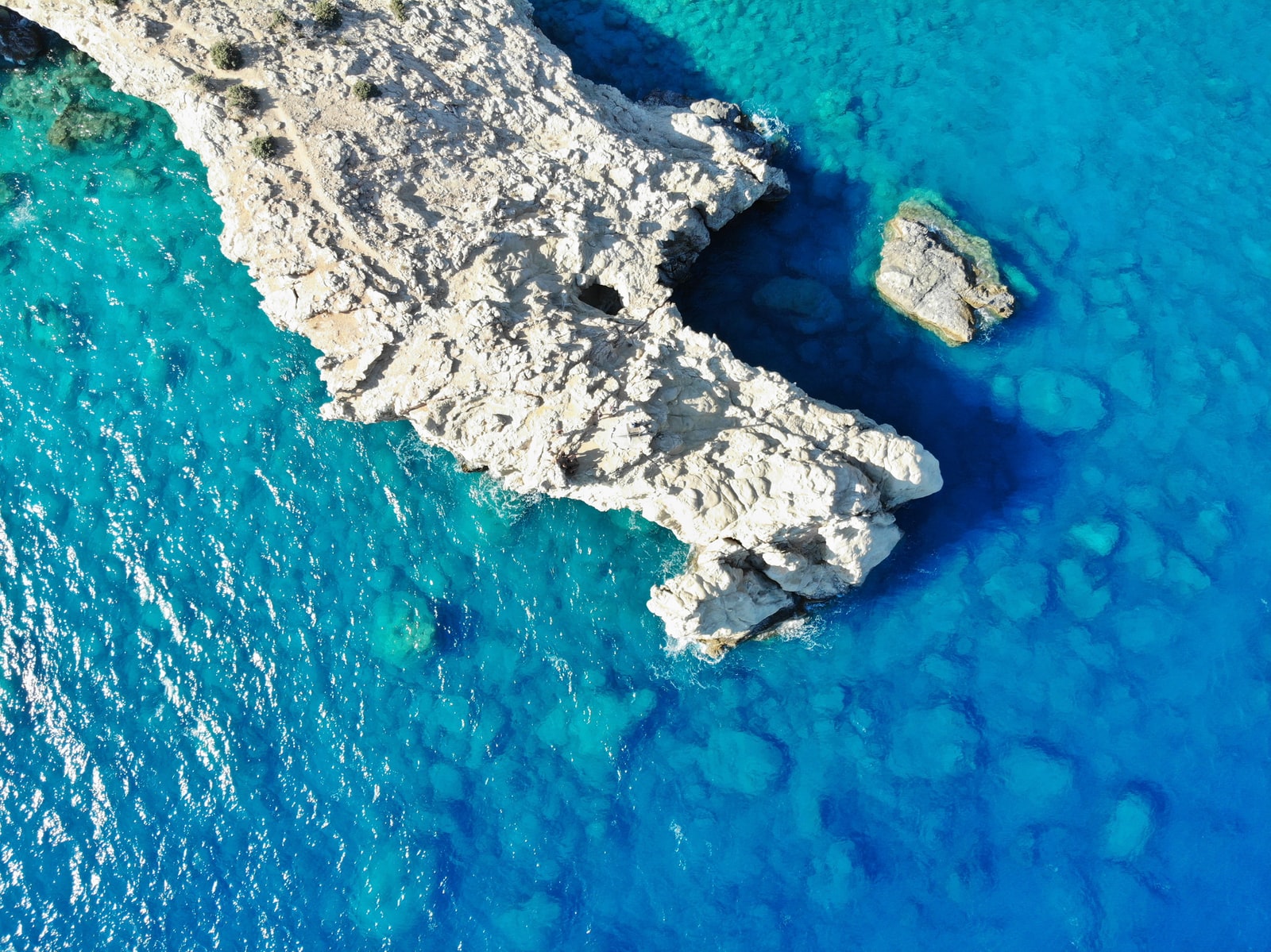 aerial view of gray and black rock formation on blue sea during daytime