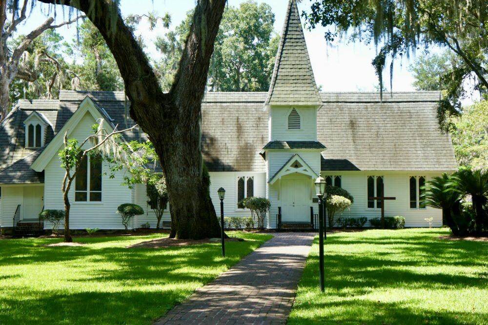 white and brown concrete house near green grass field and trees during daytime
