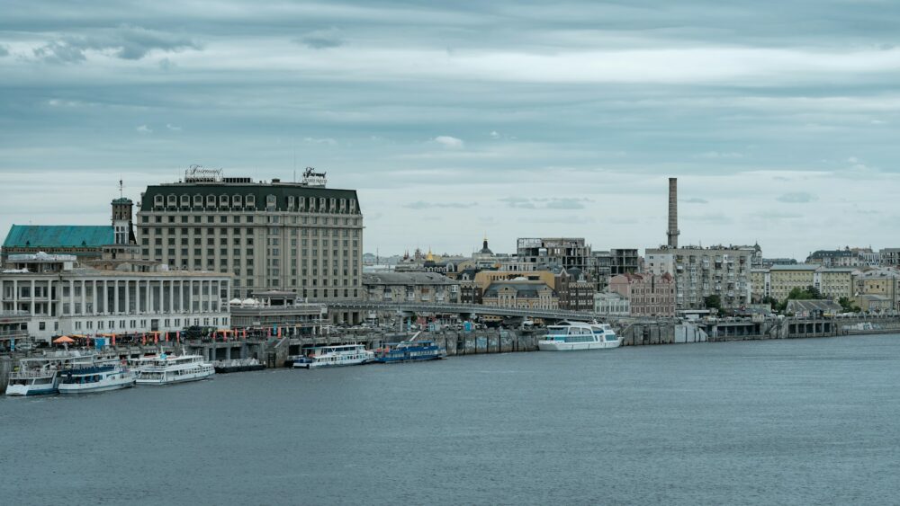 white and blue boat on water near city buildings during daytime