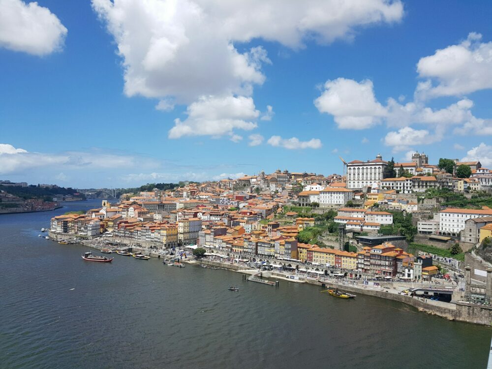 city buildings near body of water under blue and white sunny cloudy sky during daytime